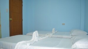 A room with two beds, a wooden door, and a light switch on the wall.