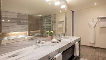 A modern bathroom with a large marble vanity, two sinks, a glass shower enclosure, and a large mirror.