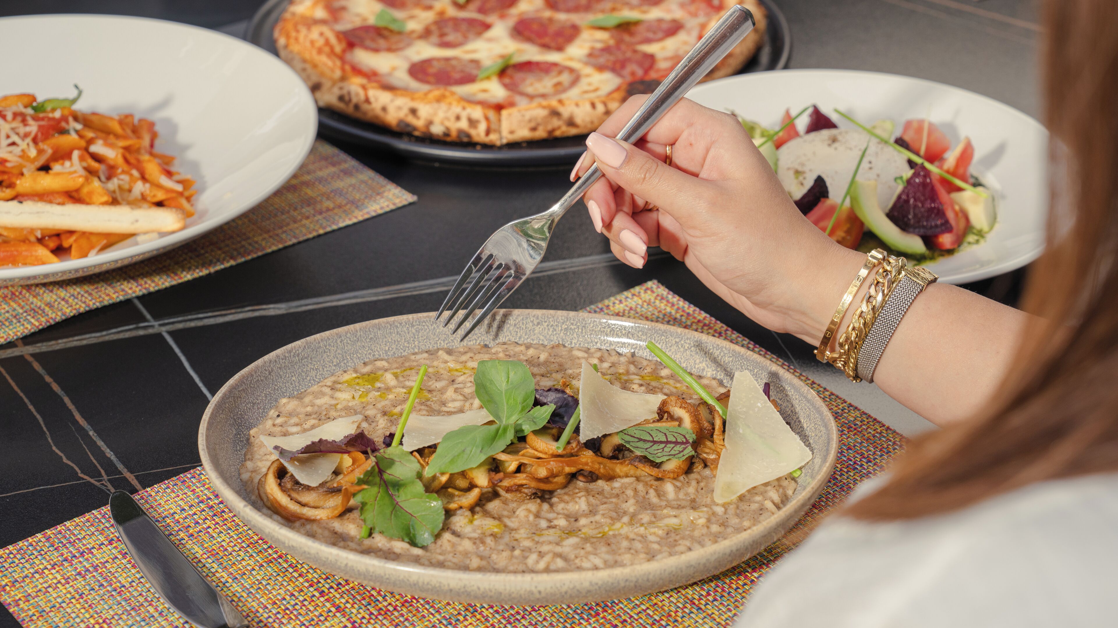 A dining table with plates of food, including pasta, pizza, and a salad.