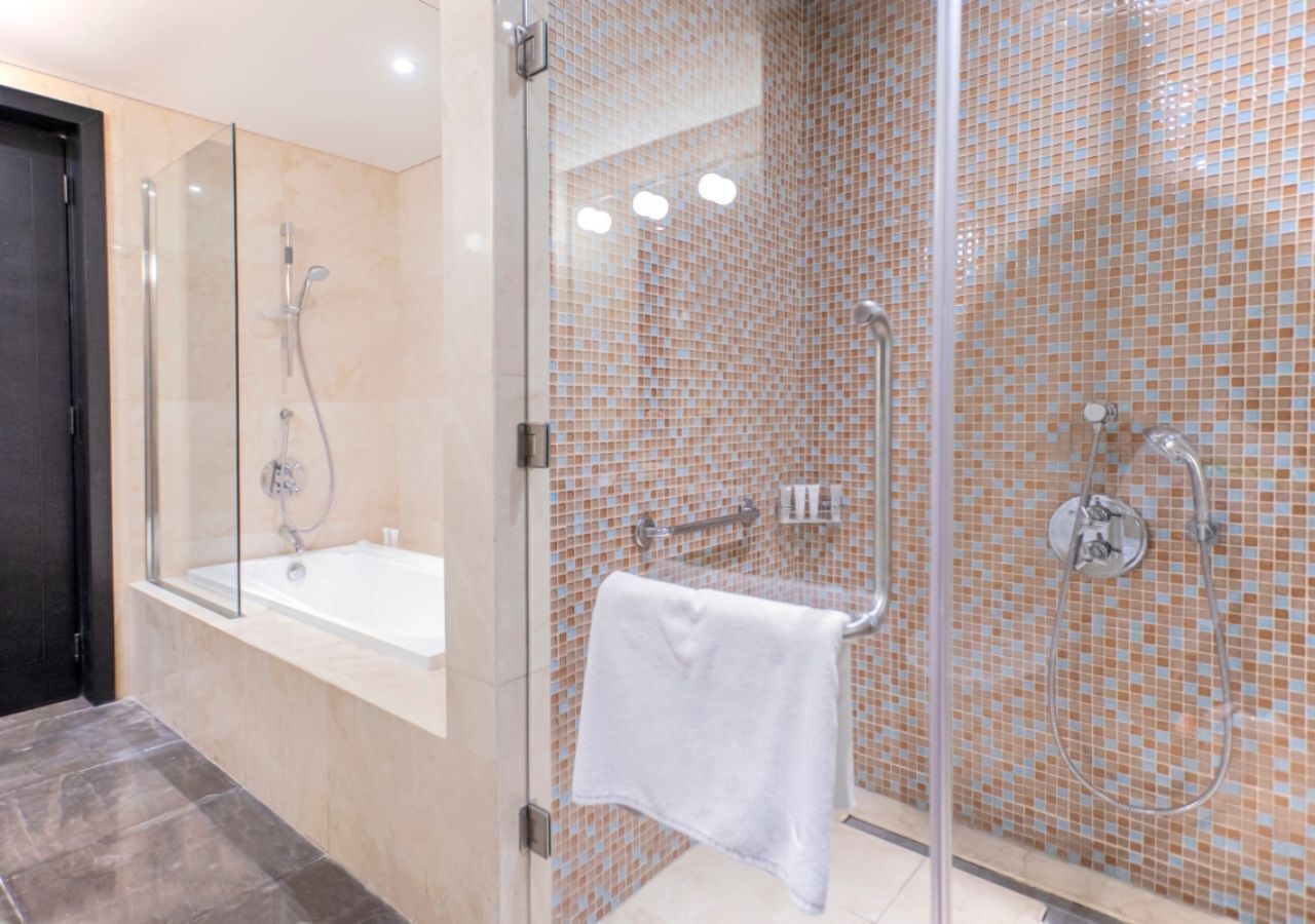 A modern bathroom with a glass-enclosed shower, a bathtub, and a tiled wall.