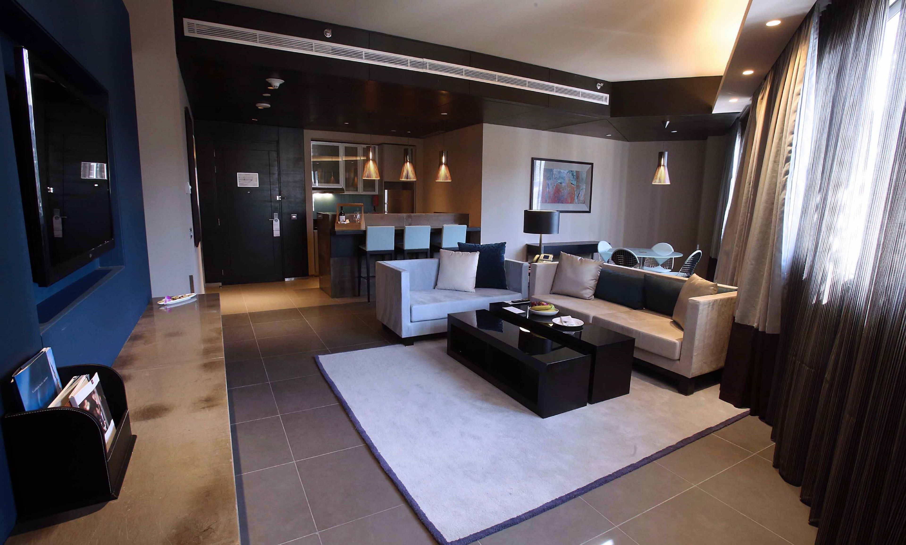 A modern living room with a sofa, coffee table, and a dining area with chairs and a table.