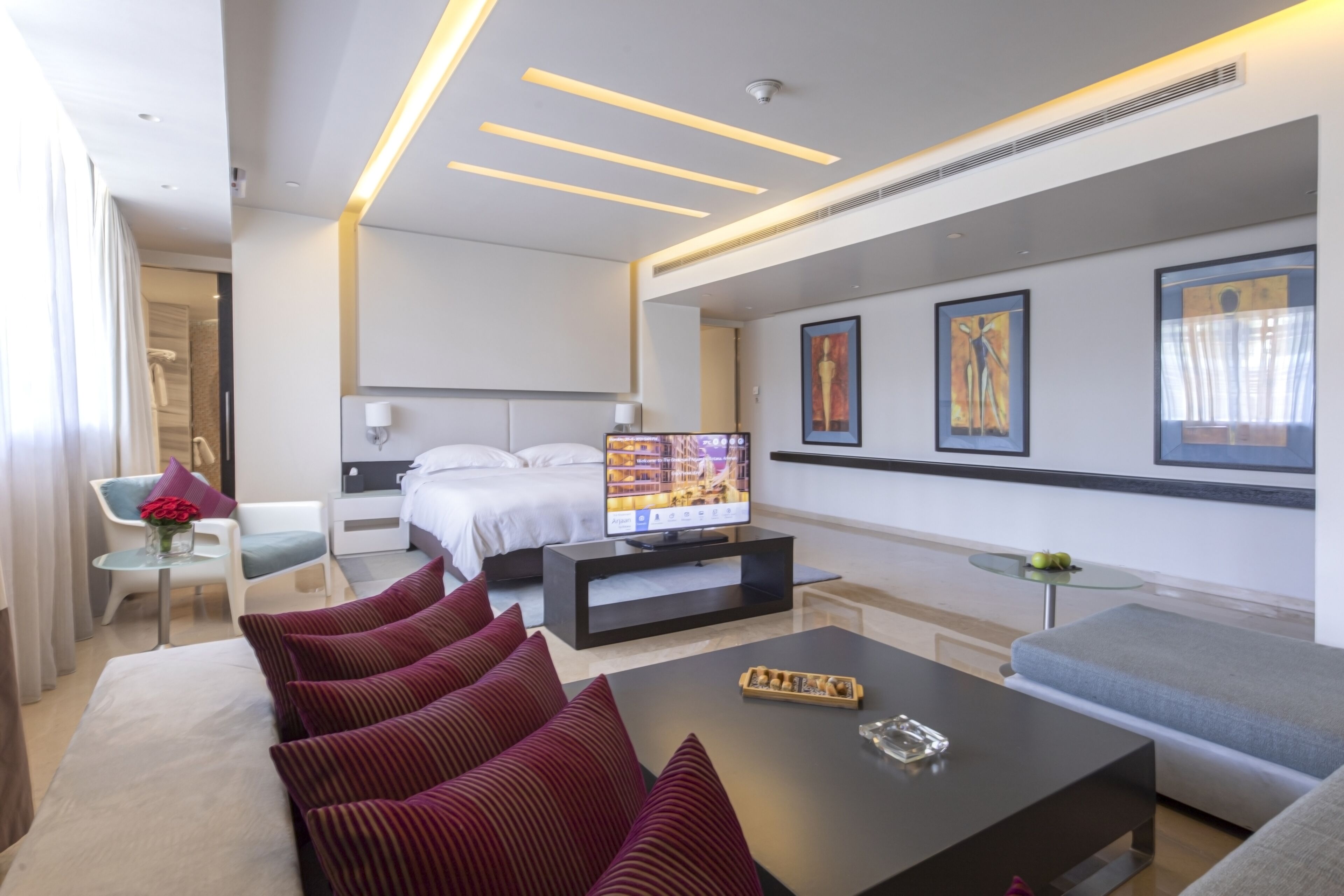 Habitació d'hotel moderna amb llit, televisió, sofà i taula de cafè.
