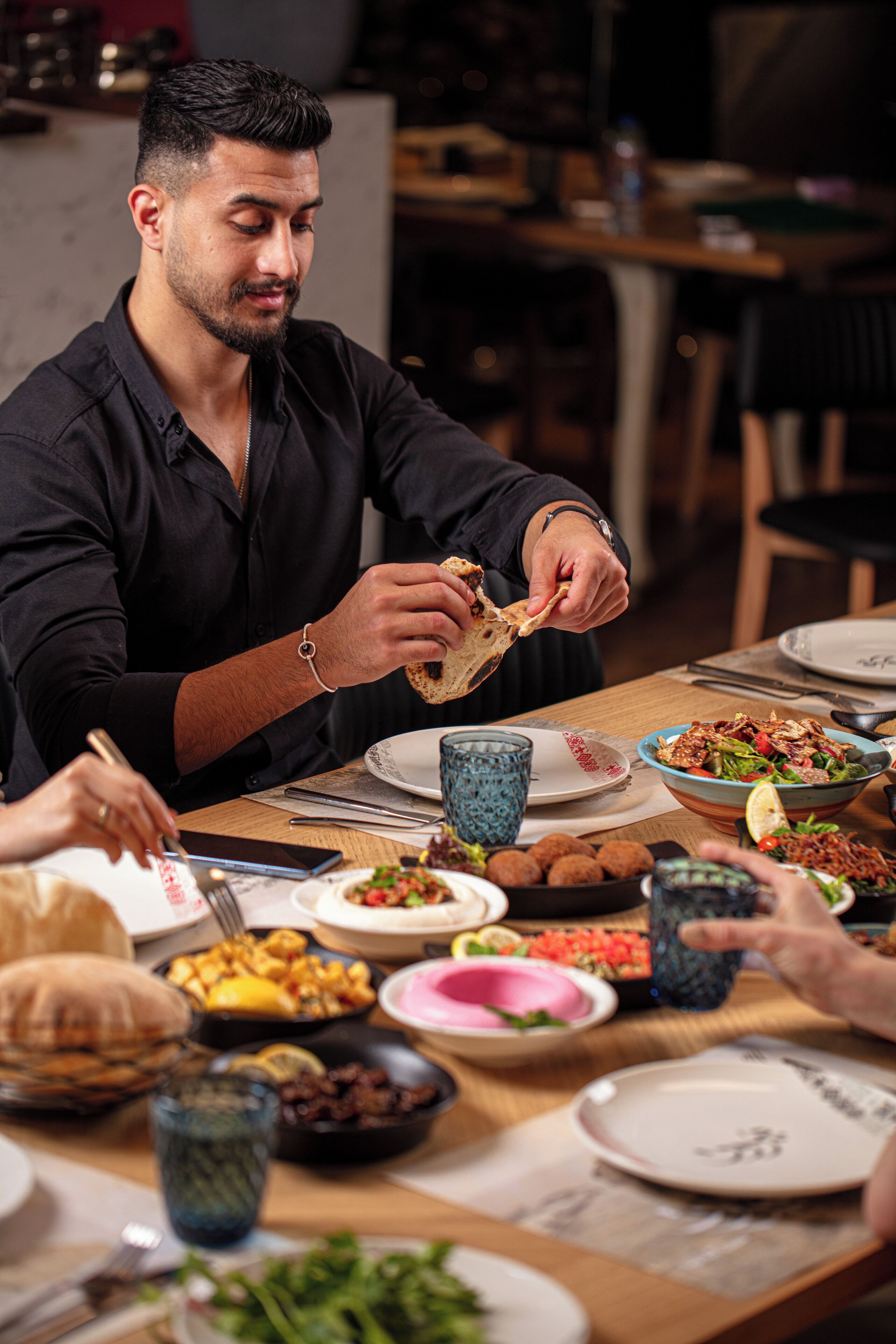 A dining table with various dishes and a person eating.