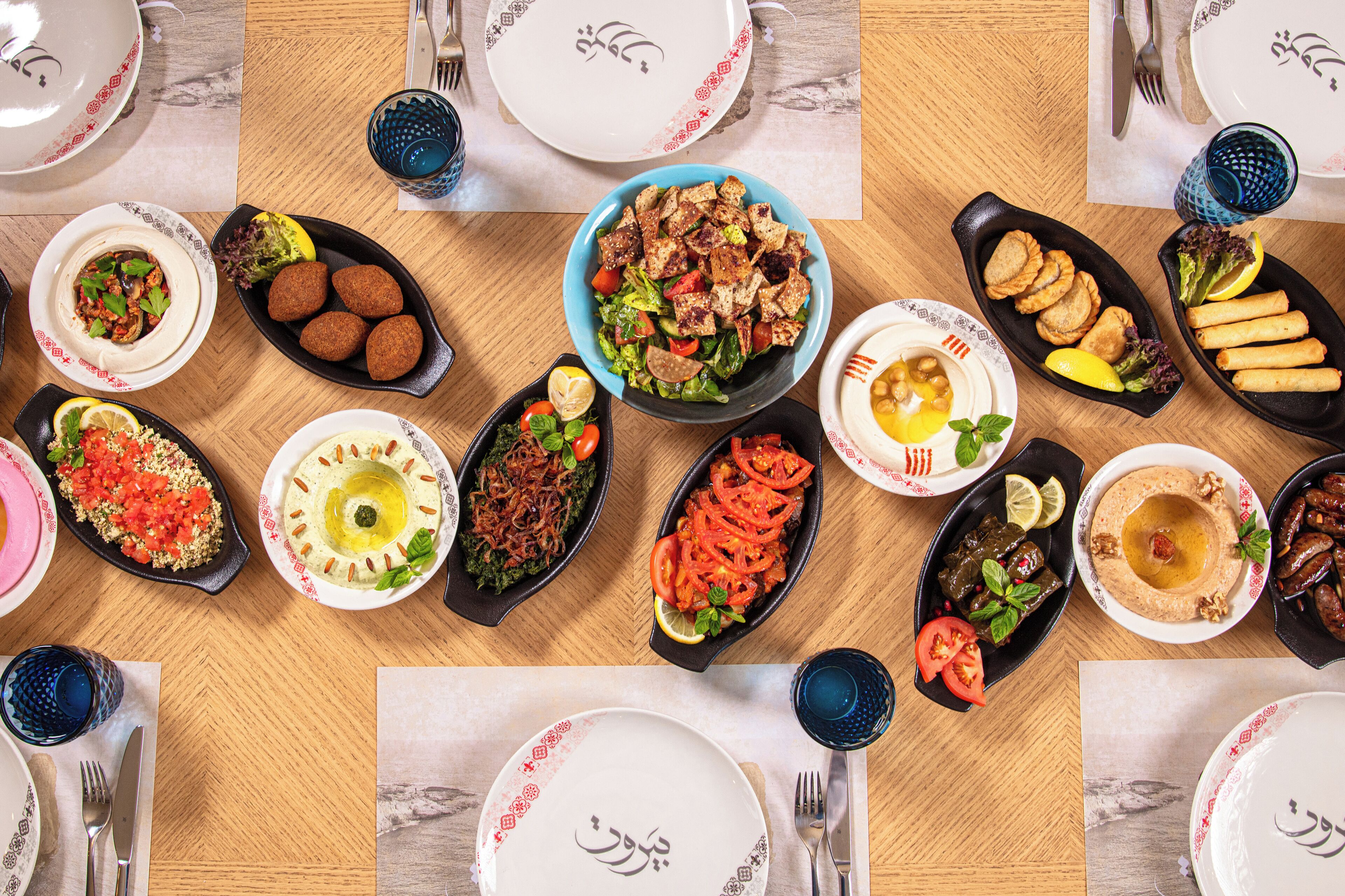A table with various dishes, including falafel, hummus, and salads, suggesting a Middle Eastern cuisine setting.