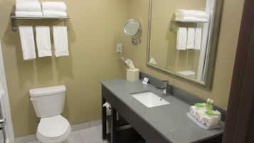 A bathroom with a toilet, sink, mirror, and towel rack.