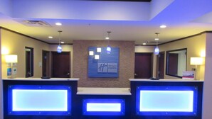 A hotel reception area with three reception desks, a central wall-mounted sign, and overhead lighting. - Holiday Inn Express & Suites Butler by IHG (Butler)