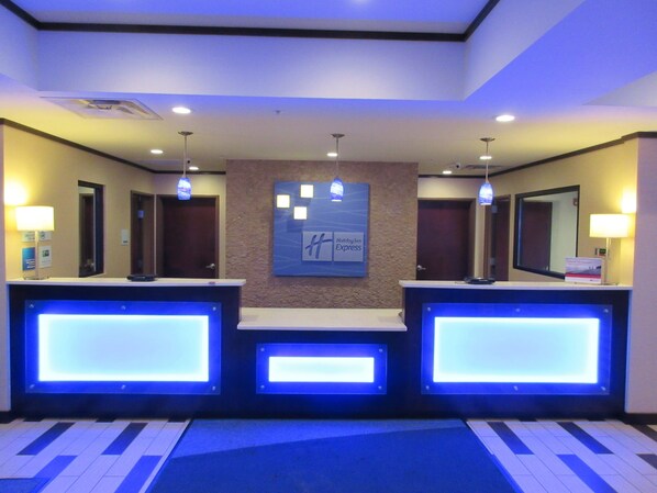 Een hotel receptie met drie balies, een centraal bevestigd bord en verlichting.
