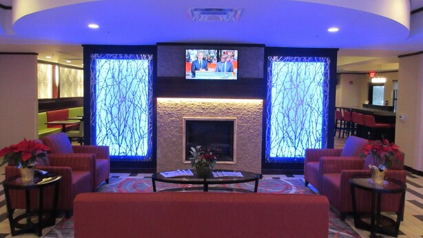 A lobby with a fireplace, seating area, and a television screen. - Holiday Inn Express & Suites Butler by IHG (Butler)