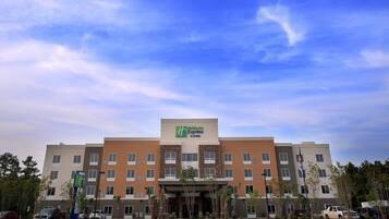 Un hotel Holiday Inn Express & Suites con un diseño arquitectónico moderno, con varios pisos y una entrada destacada.