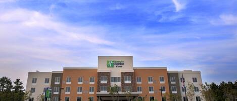 A Holiday Inn Express & Suites hotel with a modern architectural design, featuring multiple floors and a prominent entrance.