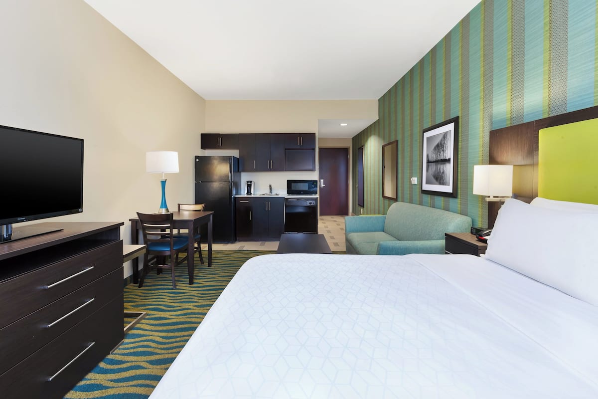 Une chambre d’hôtel comprenant un lit, un bureau avec une chaise, une télévision, une kitchenette et une salle de bain.
