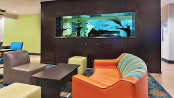 A lobby with a large aquarium, leather seating, and a patterned carpet.