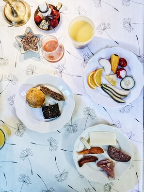 Une table de petit-déjeuner avec des assiettes de pain grillé, de confiture, de fromage et de charcuterie.