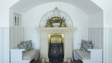A room with a fireplace, two white benches, and a decorative mantelpiece.