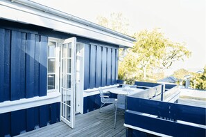 Une terrasse avec une table et des chaises, une porte et un mur extérieur bleu.