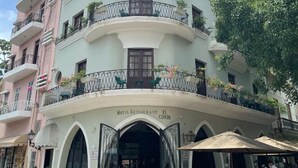 Un hotel de varios pisos con balcones, un restaurante y un letrero que indica que se trata del restaurante del hotel, llamado "El Conde".