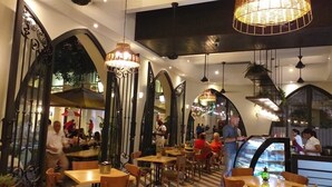 Un restaurante con techos altos en arco, lámparas colgantes y una vitrina central de cristal.