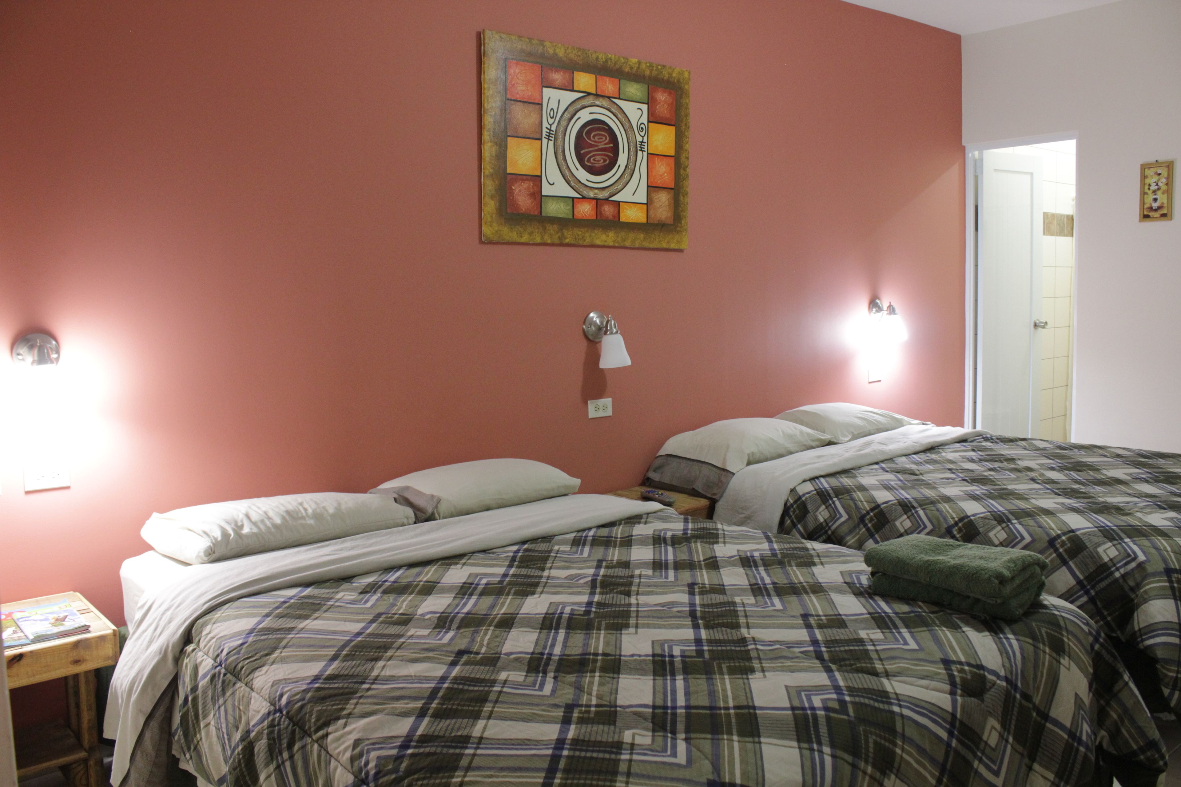 A bedroom with two beds, a wall clock, and a door.