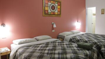 A bedroom with two beds, a wall clock, and a door.