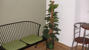 A room with a black metal bench, a tall potted plant, and a small round table with two chairs. - Dream's Hotel Puerto Rico (San Juan)