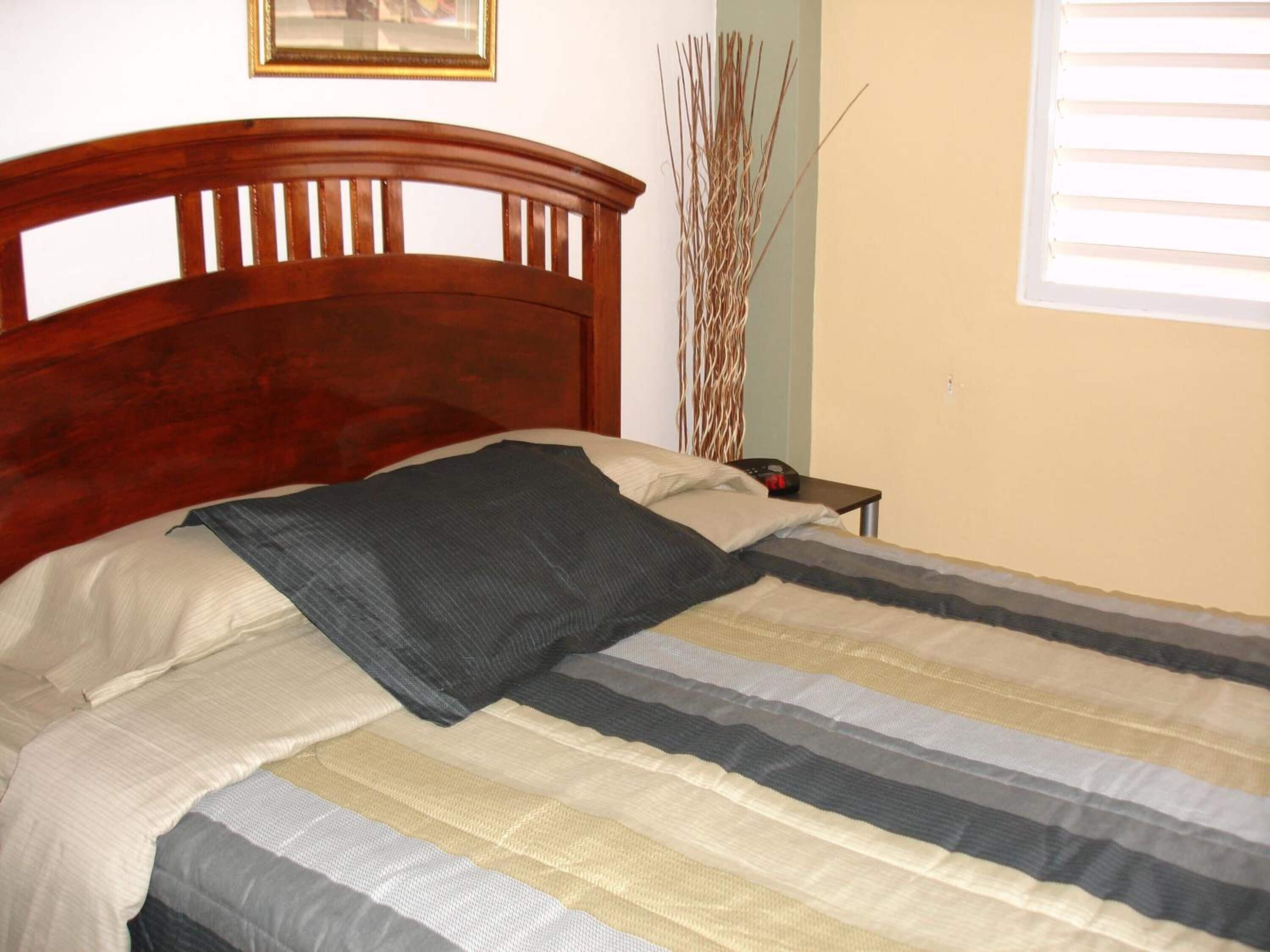 Una cama bien hecha con una colcha a rayas y un cabecero de madera.