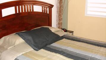 Una cama bien hecha con una colcha a rayas y un cabecero de madera.