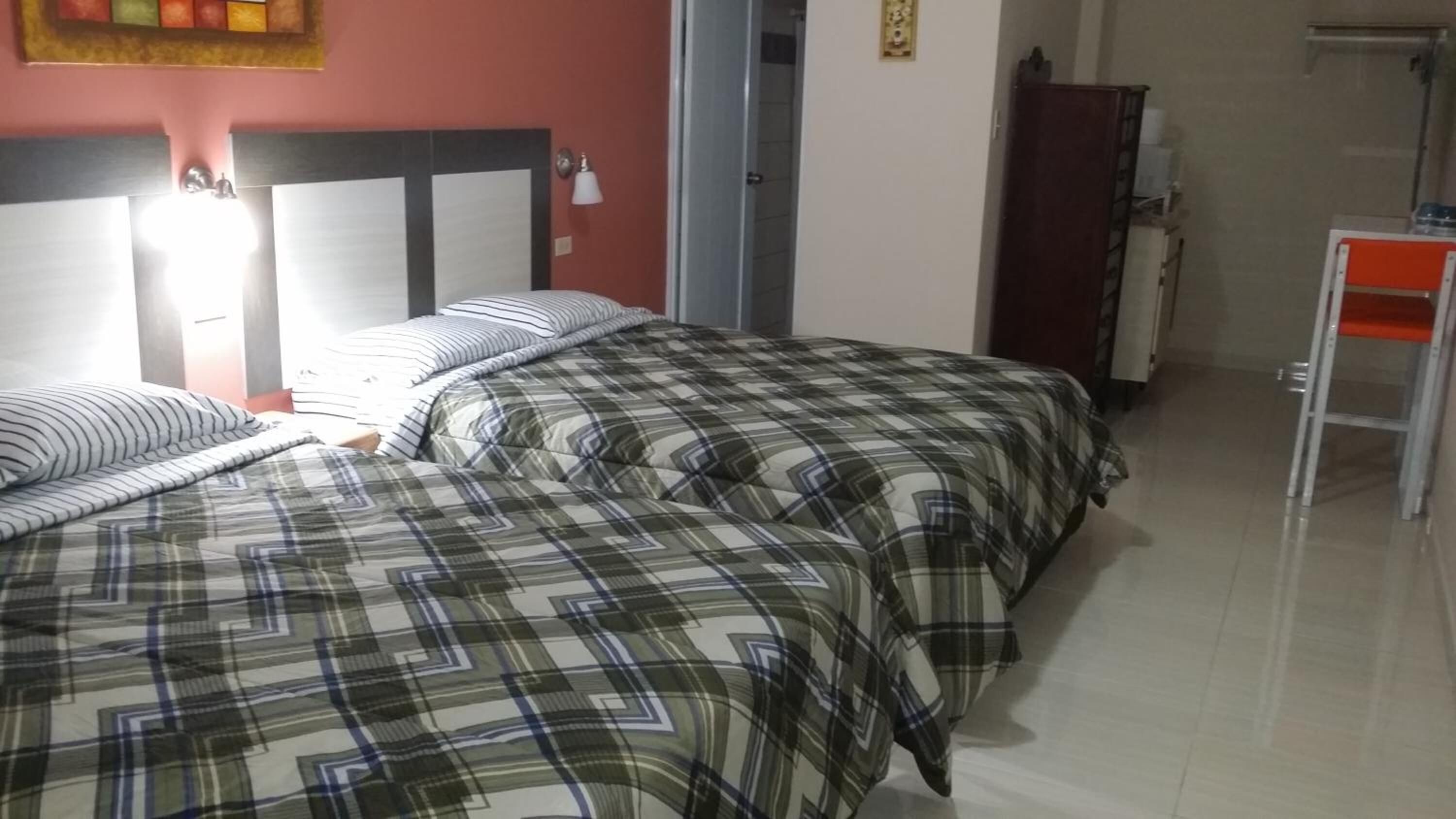 Ein Zimmer mit zwei Betten, einem Nachttisch, einem Kleiderschrank und einem kleinen Tisch.