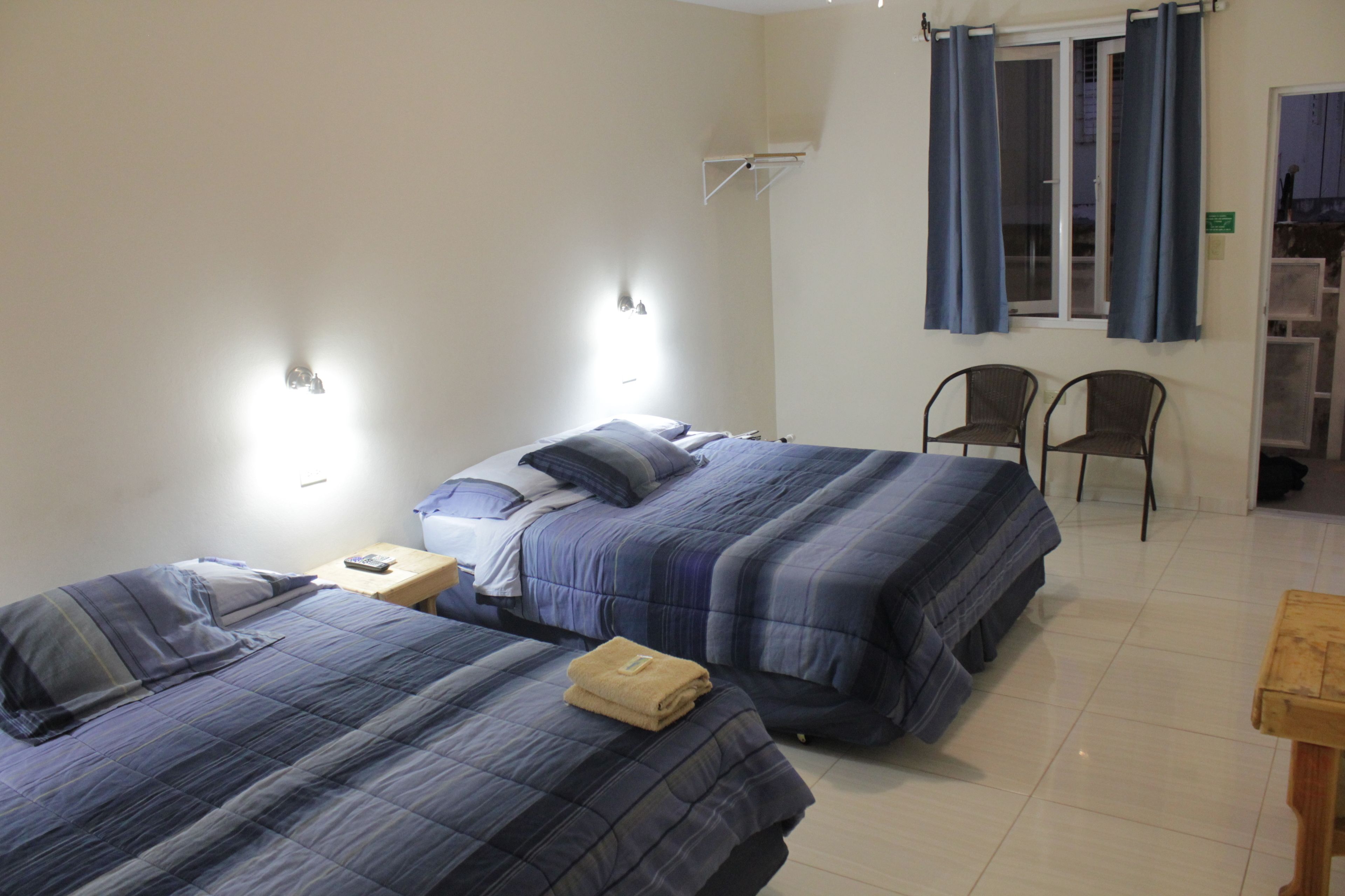 Ein Hotelzimmer mit zwei Betten, einem Nachttisch, einem Holztisch und einem Stuhl.