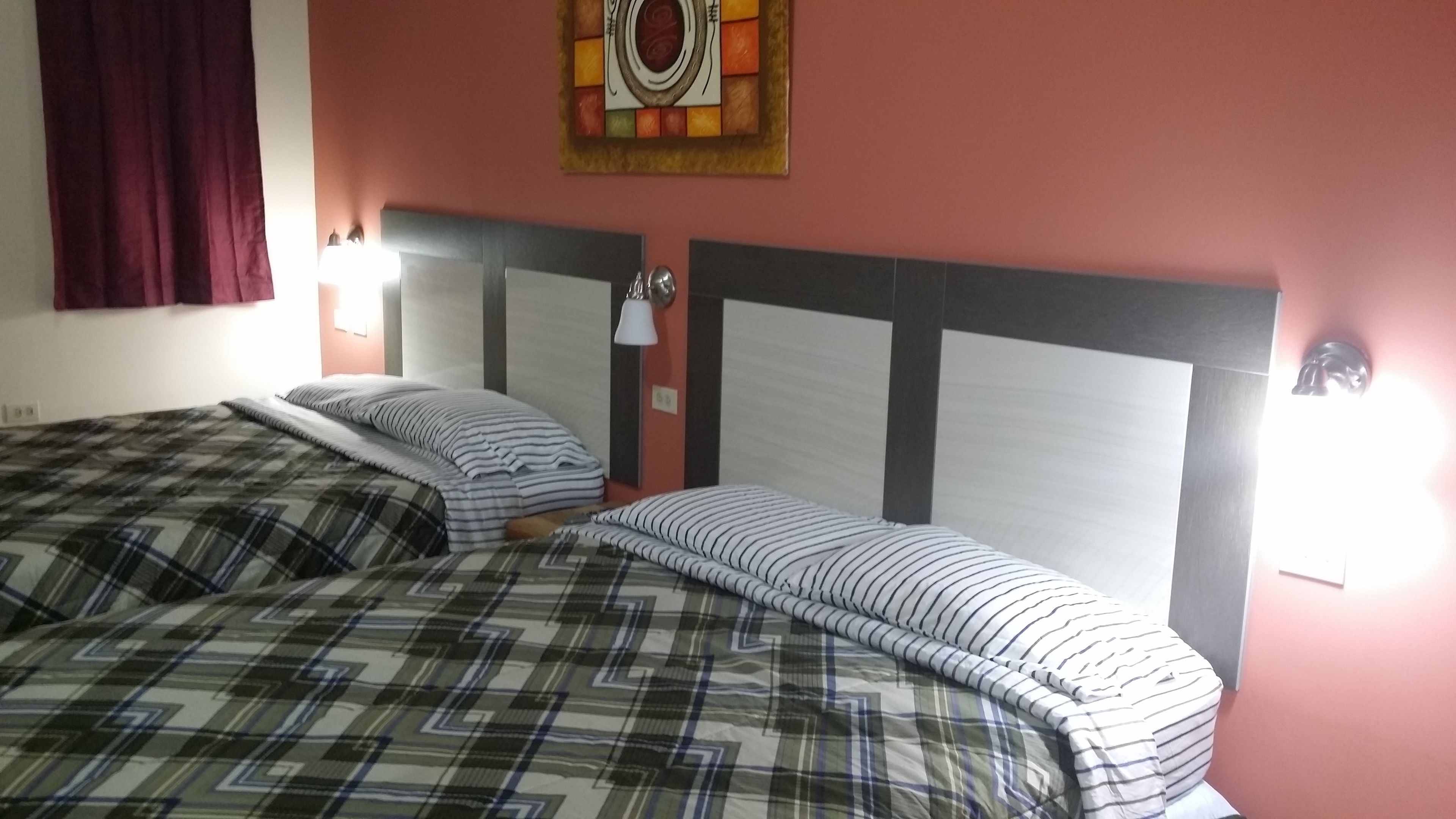 Une chambre d’hôtel avec deux lits, chacun doté d’une tête de lit et d’une lampe de chevet.