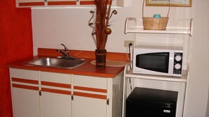A compact kitchen with a sink, a microwave, and a black refrigerator. - Dream's Hotel Puerto Rico (San Juan)