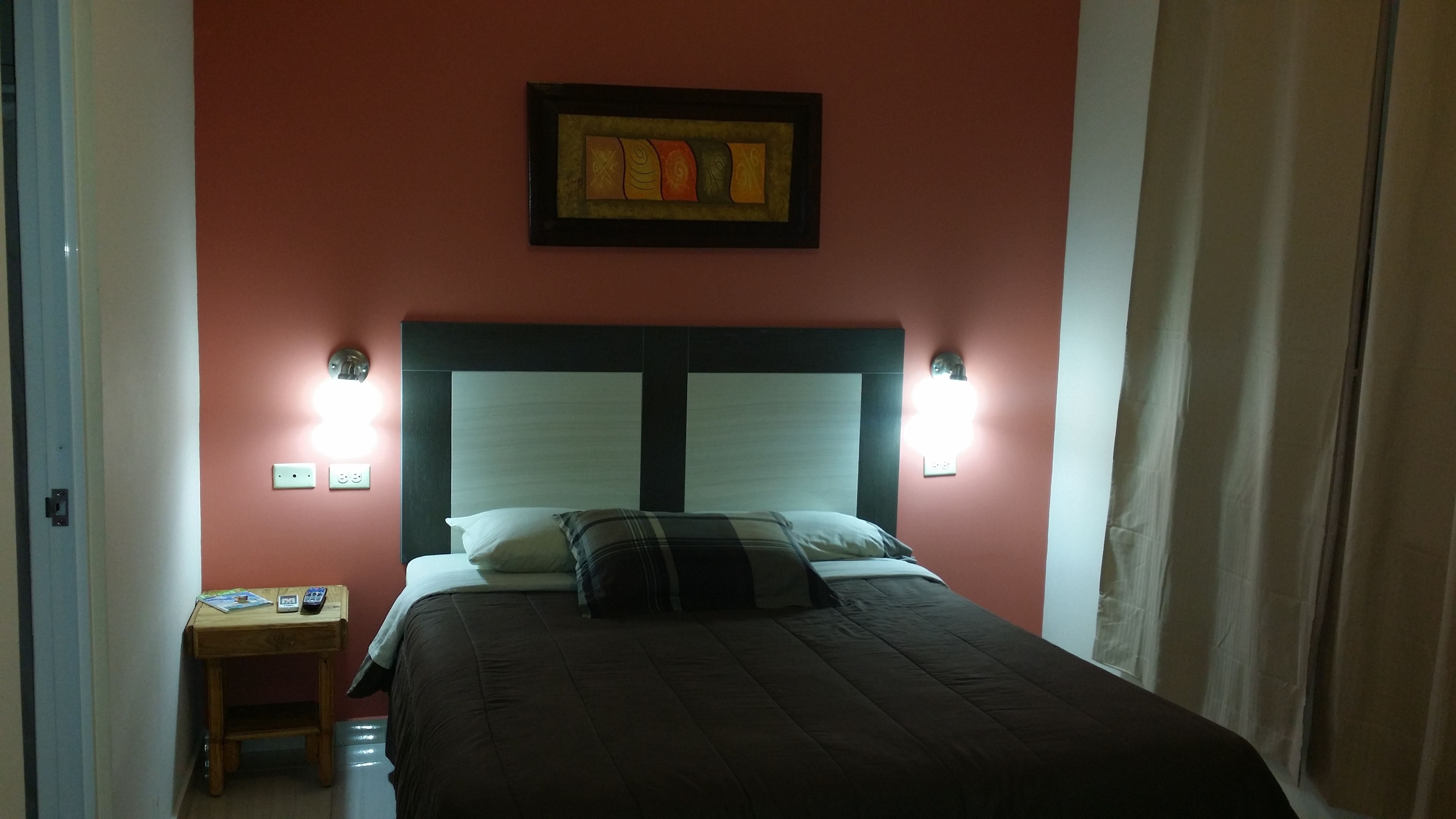 Un dormitorio con una cama, dos lámparas de noche, una mesita de noche y un cuadro en la pared.