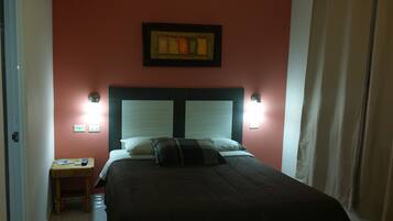 Un dormitorio con una cama, dos lámparas de noche, una mesita de noche y un cuadro en la pared.