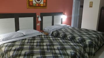 Una habitación con dos camas, cada una con ropa de cama a rayas y cuadros. Hay un reloj de pared y un cuadro enmarcados sobre las camas.