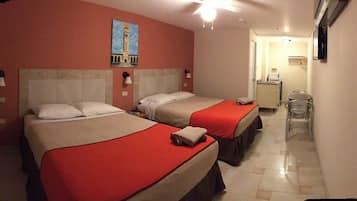 Two beds with red bedspreads and white pillows, a painting, ceiling fan, and desk with chair.