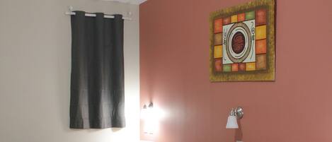 A hotel room with two beds, a ceiling fan, a painting on the wall, and a window with curtains.