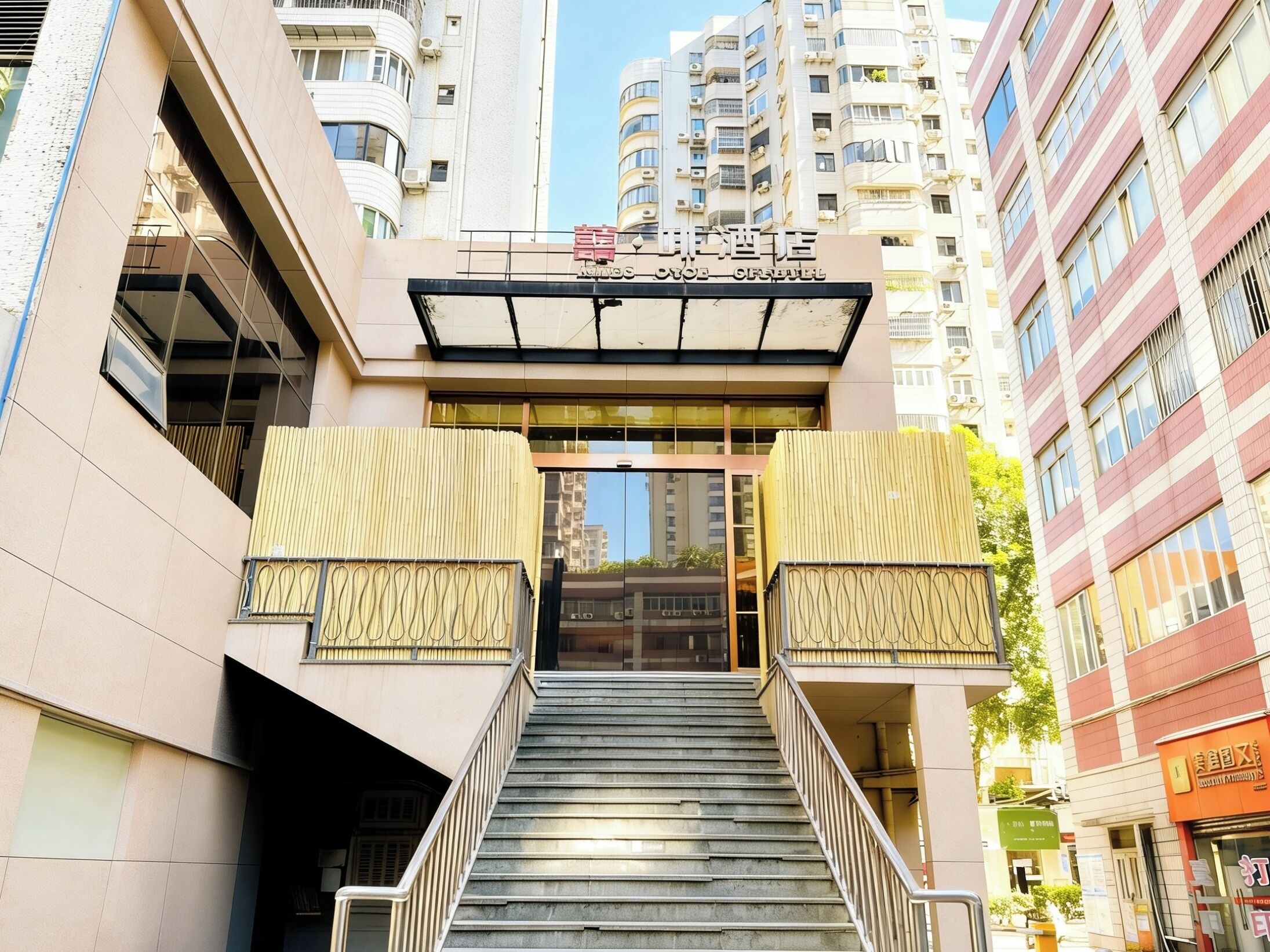 Entrada de un hotel con una escalera que conduce a la recepción, rodeada de edificios modernos.