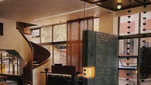 Een moderne lobby met een spiltrap, zithoeken en grote ramen.