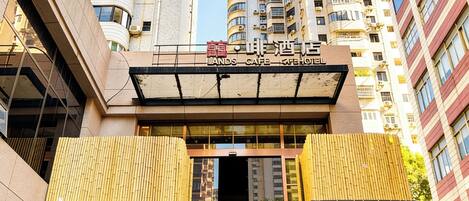 Un edificio con un cartel que dice 'LANDS CAFE HOTEL' y un diseño arquitectónico moderno con balcones.