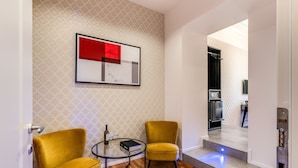 A modern living room with two yellow armchairs, a glass coffee table, and a framed abstract artwork on the wall. - Arenula Suites (Rome)