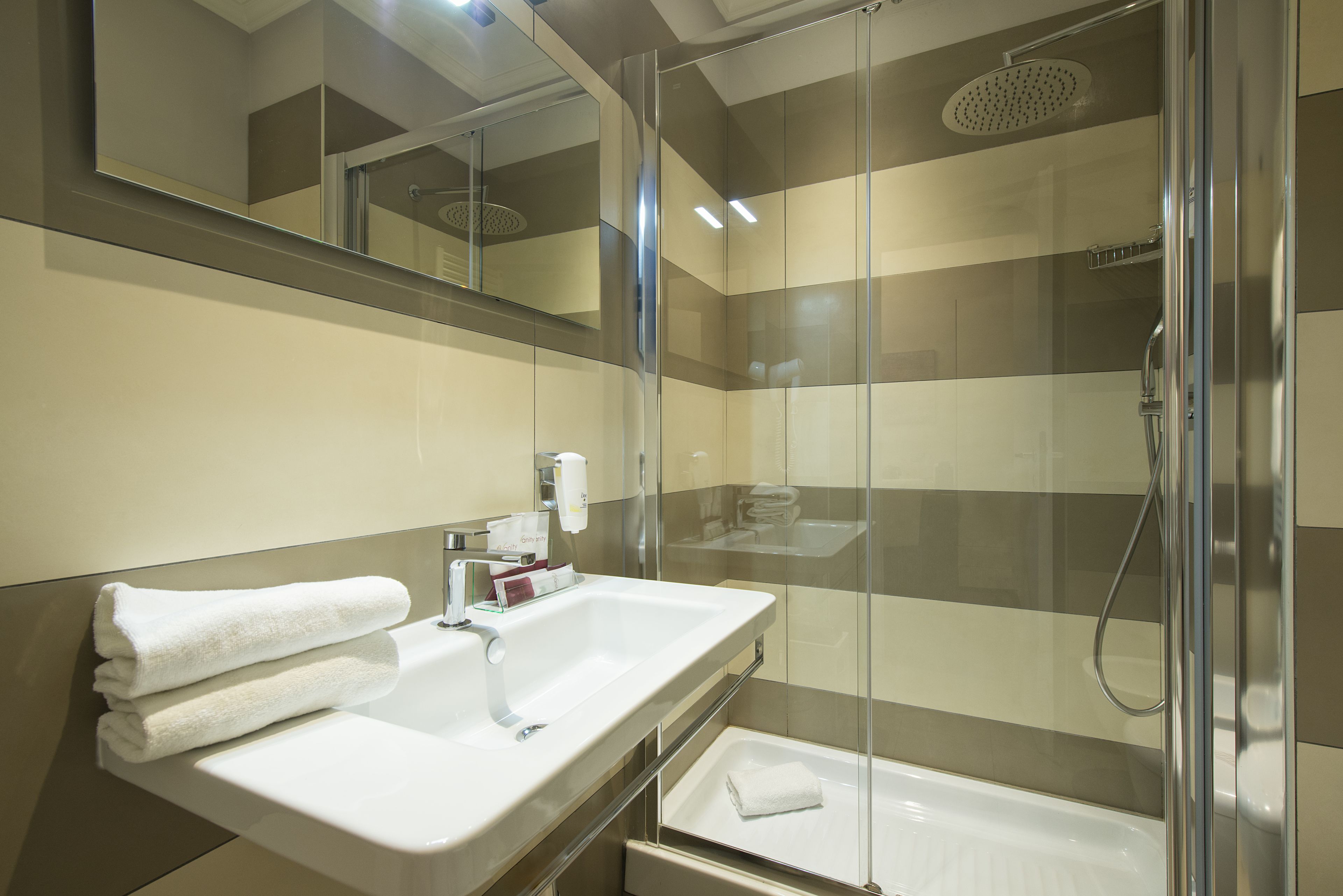 Un baño moderno con ducha de vidrio, un lavabo blanco y un espejo encima.