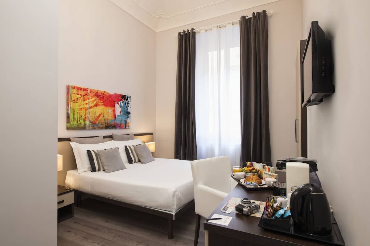 Une chambre d’hôtel avec un lit, un bureau doté d’une machine à café, une télévision et un tableau au mur.