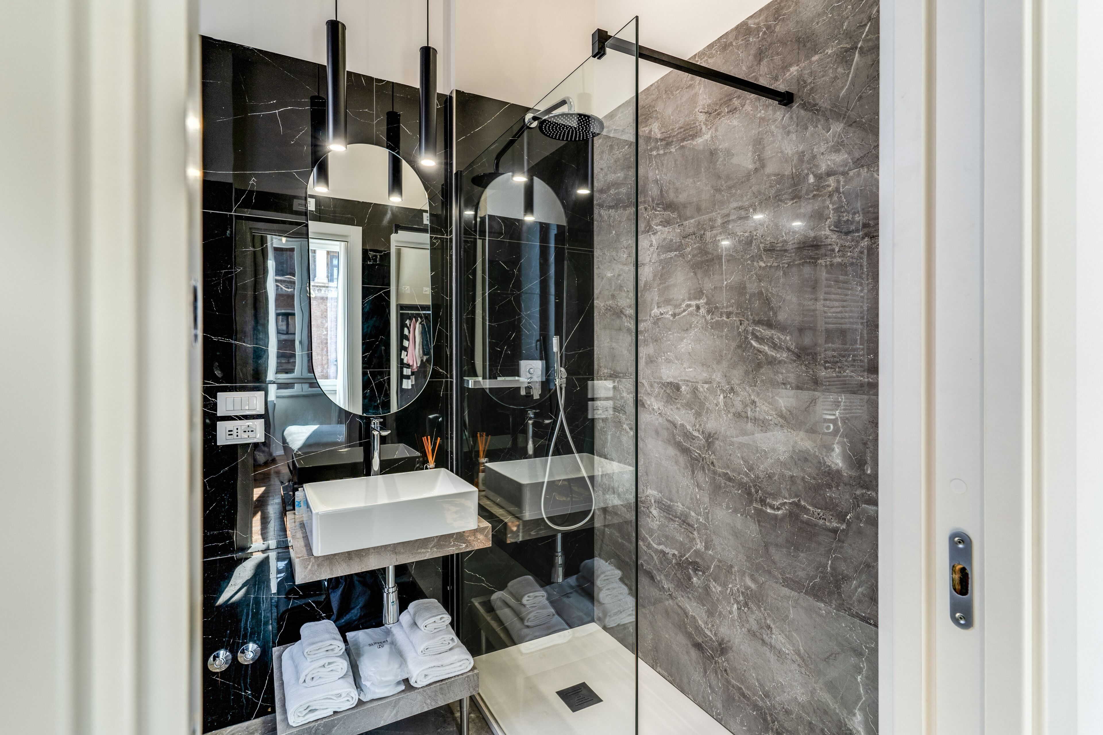A modern bathroom with a glass-enclosed shower, a white sink, and a large mirror.