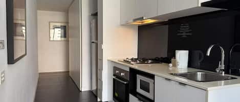 Una cocina moderna con armarios blancos, un lavaplatos de acero inoxidable, una estufa y un microondas.