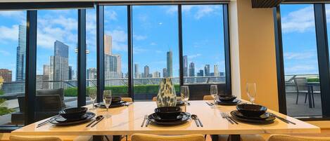 Un comedor con vista a la ciudad, ventanas amplias y una mesa dispuesta para dos.