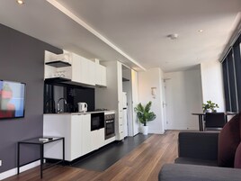 Eine moderne Küche mit weißen Schränken, einer schwarzen Arbeitsplatte und Edelstahlgeräten. Ein Essbereich mit Tisch und Stühlen lädt zum Verweilen ein, und ein großes Fenster sorgt für natürliches Licht.