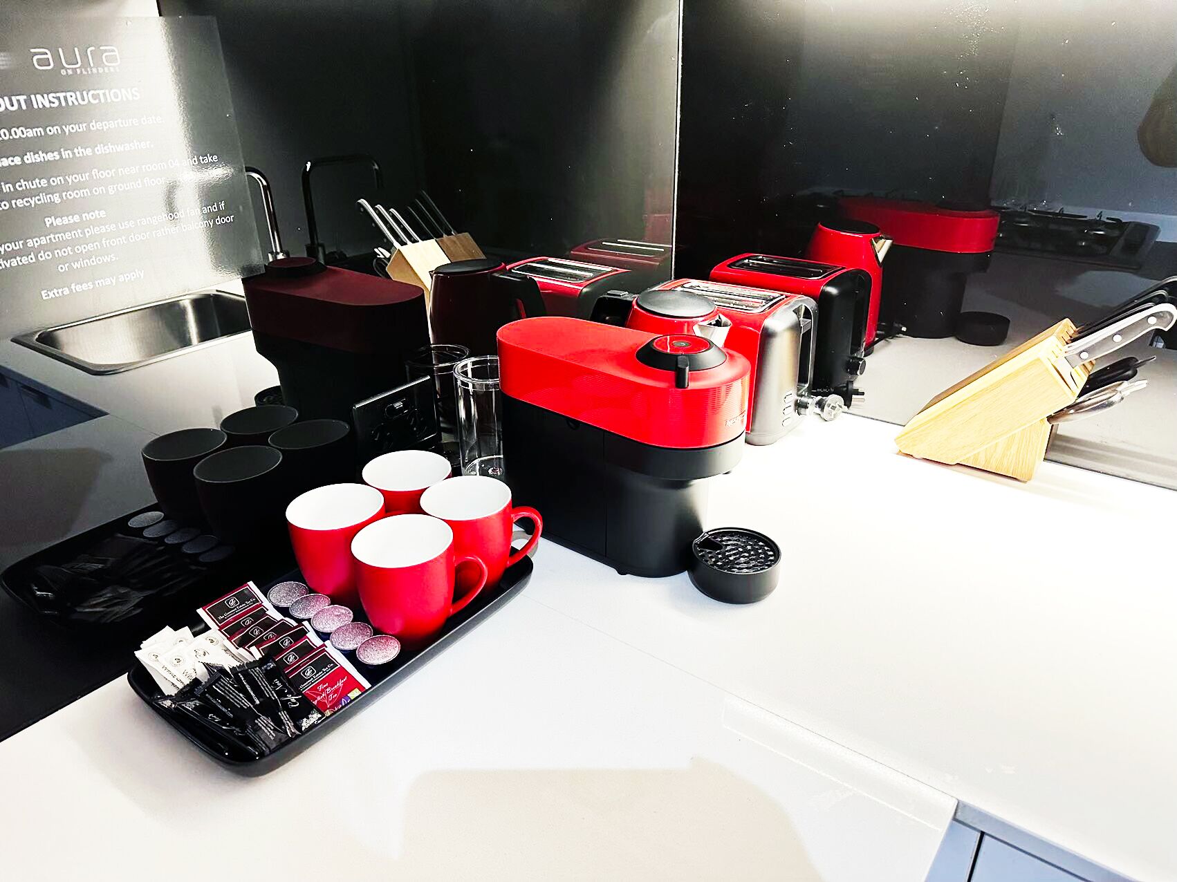 A kitchen counter with a toaster, coffee maker, mugs, and a knife block.