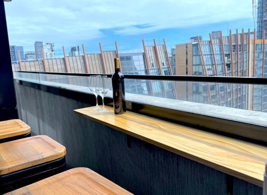 A high-rise bar with a city view, wooden bar counter, and two stools.