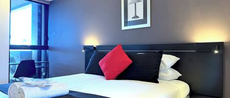 Une chambre d’hôtel moderne avec un grand lit, une table de chevet, une chaise et une fenêtre.
