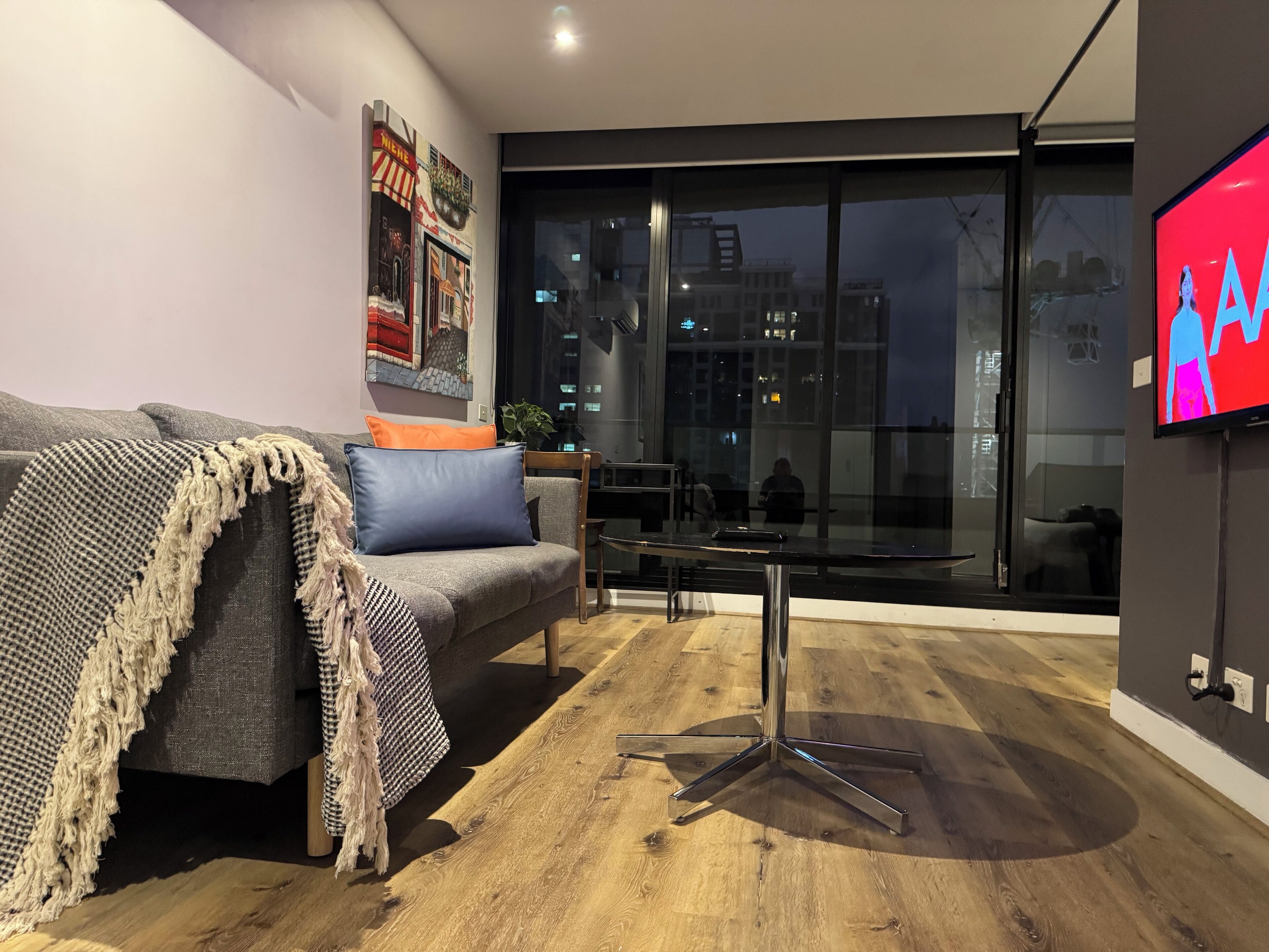 A modern living room with a grey sofa, a coffee table, and a TV mounted on the wall.