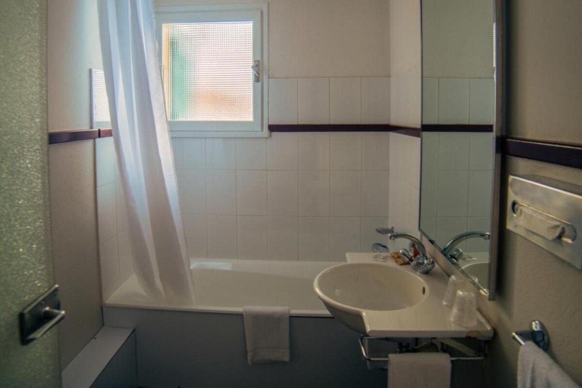 A bathroom with a bathtub, sink, and mirror.